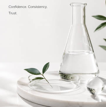 Vaso de vidrio transparente sobre una superficie de mármol con texto sobre ingredientes centrados en la calidad para marcas.